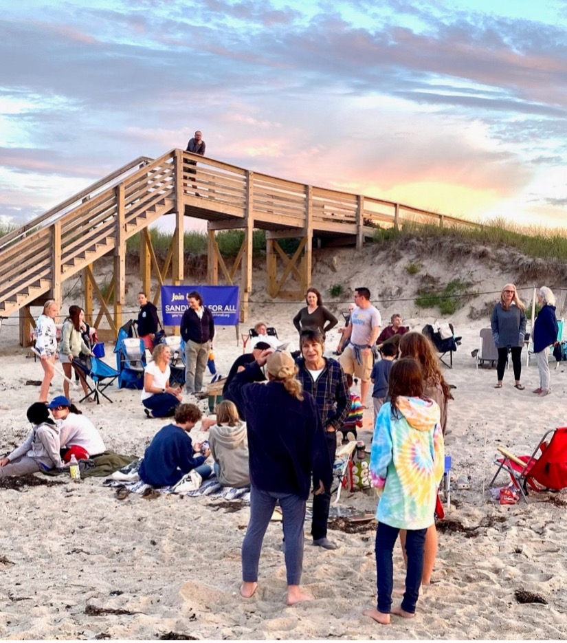 People gathered together on a beach talking